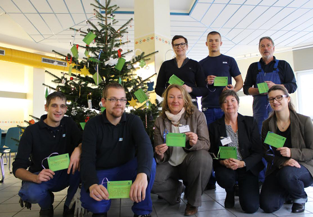 Vom Nikolaus für gut befunden: Christian Nicolaus (ganz links) und weitere Mitarbeiter und Mitarbeiterinnen von B+K sowie Vertreterinnen der Wohngruppen vor dem geschmückten Weihnachtsbaum in der Kantine. (Foto: B+K)