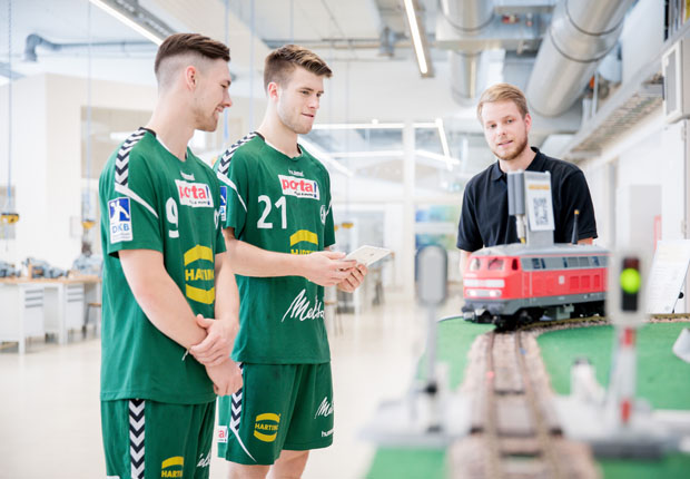 Niklas Kutschan (Auszubildender zum Mechatroniker, rechts) erklärt die Funktionsweise der Eisenbahn im Zusammenarbeit mit der MICA®. (Foto: HARTING)