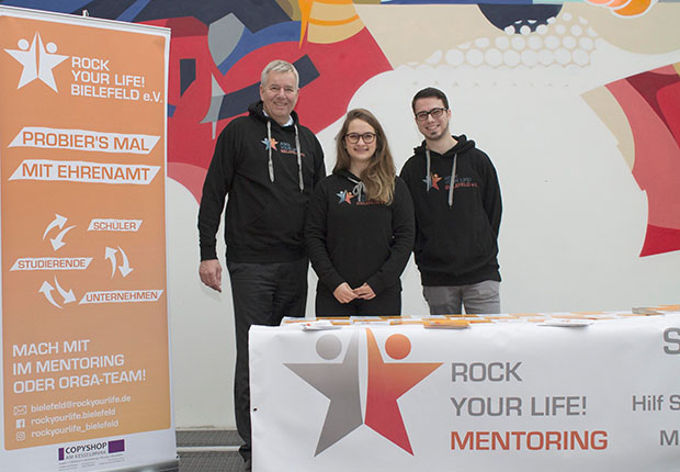 Vanessa Neumann (Mitte) und Tim Wagner (rechts) freuen sich über den Besuch von Holger Piening (links) an ihrem Stand in der Uni Bielefeld. ROCK YOUR LIFE! Bielefeld e.V. – Schülerinnen und Schülern den Schritt in die berufliche Zukunft vereinfachen. (Foto: Piening GmbH)