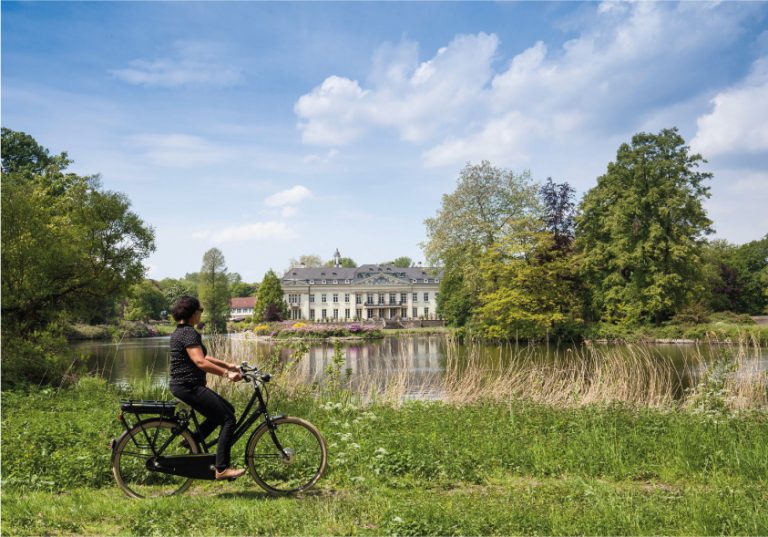 Mit Abstand unterwegs: Auf der 100 Schlösser Route winken imposante Bauwerke von nah und fern, wie hier das Schloss Varlar. Fahrradfahrerin vor Schloss Varlar © Münsterland e.V./Hans Zaglitsch