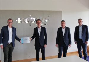 Staatssekretär Stefan Muhle überreicht Marcel Schrage, Ver-trieb, Jürgen Hartkemeyer, Leiter Vertrieb und Heinz-Peter Beste, Geschäftsführer, die Auszeichnung. - Foto: Koch International