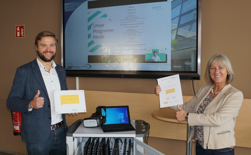 Medienkoordinator Marcel Mrotzek und Schulleiterin Susanne Tietje-Groß mit dem noch anzubringenden Schild „Digitale Schule“ sowie einem Tablet-Wagen. - Foto: HANSE-Berufskolleg