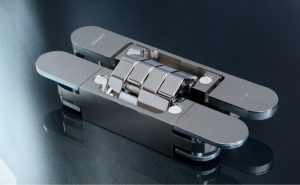 Das „Pivota DX 61 3-D“ in der Oberfläche poliert vernickelt: aktuelles Beispiel für ein verdeckt liegendes, dreidimensional justierbares Band für stumpf einschlagende Türen. In der „Design+“-Version decken magnetisch gehaltene Platten die Schraubenbereiche und die Ausfräsung in der Türzarge ab. Foto: BaSys
