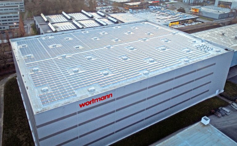 Das Hochregallager mit PV-Anlage (im Vordergrund) und die Hauptverwaltung mit Outlet (Im Hintergrund). - Foto: Wortmann Gruppe