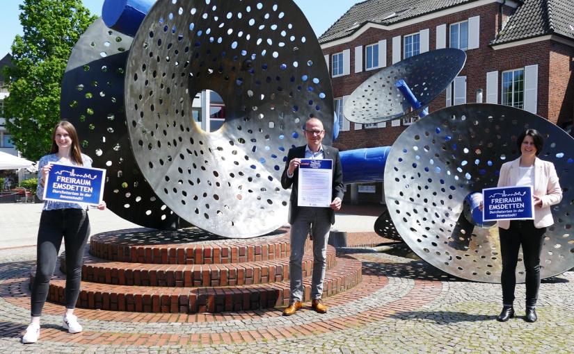 Michelle Dresemann (l.) und Nicole Mahlmann (r.) vom ServiceCenter Innenstadt der Stadt Emsdetten mit Bürgermeister Oliver Kellner (m.) vor dem Morgentaubrunnen in Emsdetten. - Foto: Stadt Emsdetten