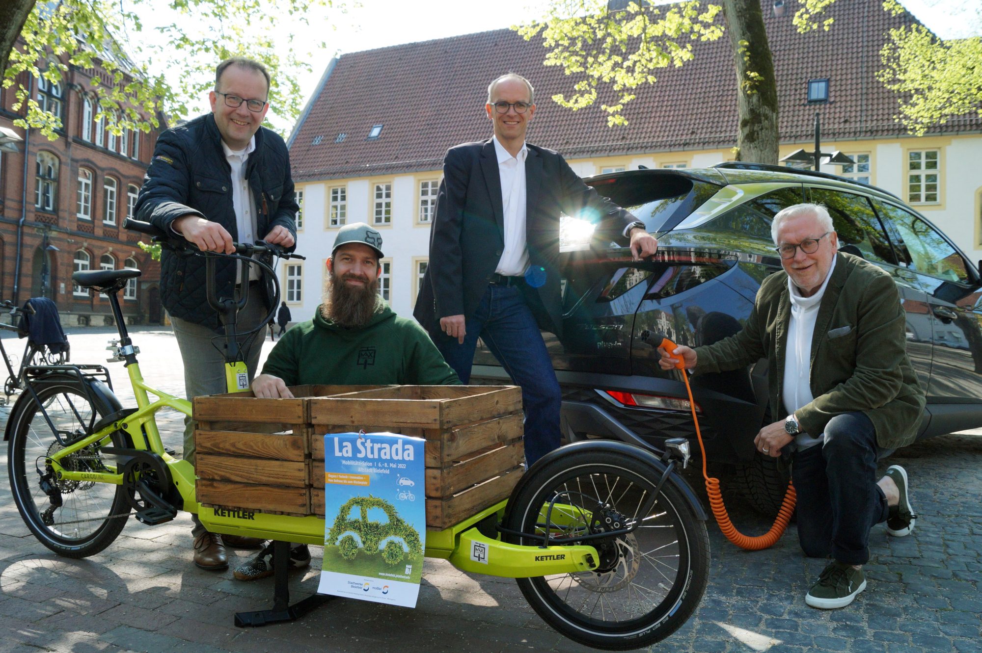 Martin Knabenreich (Bielefeld Marketing, v. l.), Michael Holzweißig (MAX Cargobike), Martin Uekmann (Stadtwerke Bielefeld) und Ralf Eigenrauch (Agentur Eigenrauch & Partner) stellen das Konzept der La Strada 2022 auf dem Klosterplatz vor. Lastenräder, Autos mit Elektro-Antrieb, Sharing-Angebote sowie Innovationen des öffentlichen Nahverkehrs spielen vom 6. bis 8. Mai eine zentrale Rolle in der Bielefelder Altstadt. (Foto: Bielefeld Marketing GmbH)
