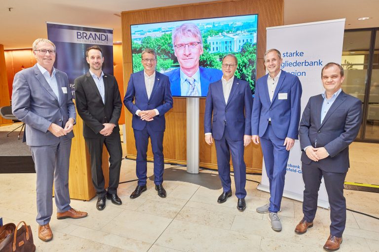 Akteure beim wirtschaftspolitischen Abend der IHK: (v.li.) Harald Grefe, Timo Fratz, Michael Deitert, Dr. Franz Tepper, Christian Nüßer und Pascal Wizenti. Auf dem Bildschirm der zugeschaltete ZDF-Journalist Elmar Theveßen (Foto: Volksbank Gütersloh)