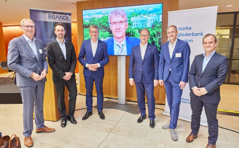 Akteure beim wirtschaftspolitischen Abend der IHK: (v.li.) Harald Grefe, Timo Fratz, Michael Deitert, Dr. Franz Tepper, Christian Nüßer und Pascal Wizenti. Auf dem Bildschirm der zugeschaltete ZDF-Journalist Elmar Theveßen (Foto: Volksbank Gütersloh)