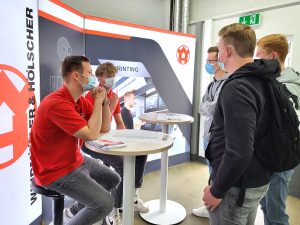 Die Auszubildenden Cedric Groppe und Jan-Paul Fledderjohann erklären Schülern die Aufgaben und den Ausbildungsverlauf des Industriekaufmanns (Foto: WINDMÖLLER & HÖLSCHER KG)