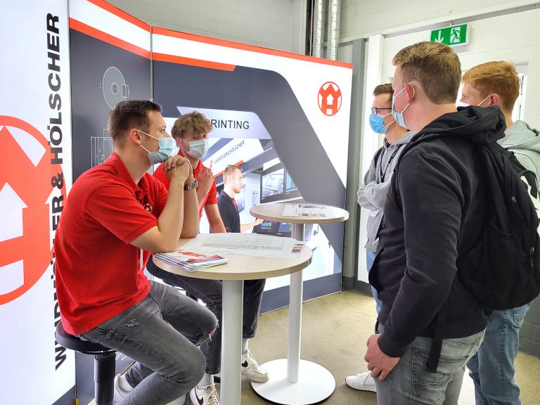Die Auszubildenden Cedric Groppe und Jan-Paul Fledderjohann erklären Schülern die Aufgaben und den Ausbildungsverlauf des Industriekaufmanns (Foto: WINDMÖLLER & HÖLSCHER KG)
