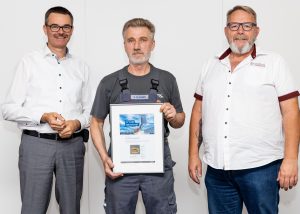 COO, Alexander Dolipski und Head of Production, Ingo Barth ehren Valentin Klassen. (Foto: Denios)
