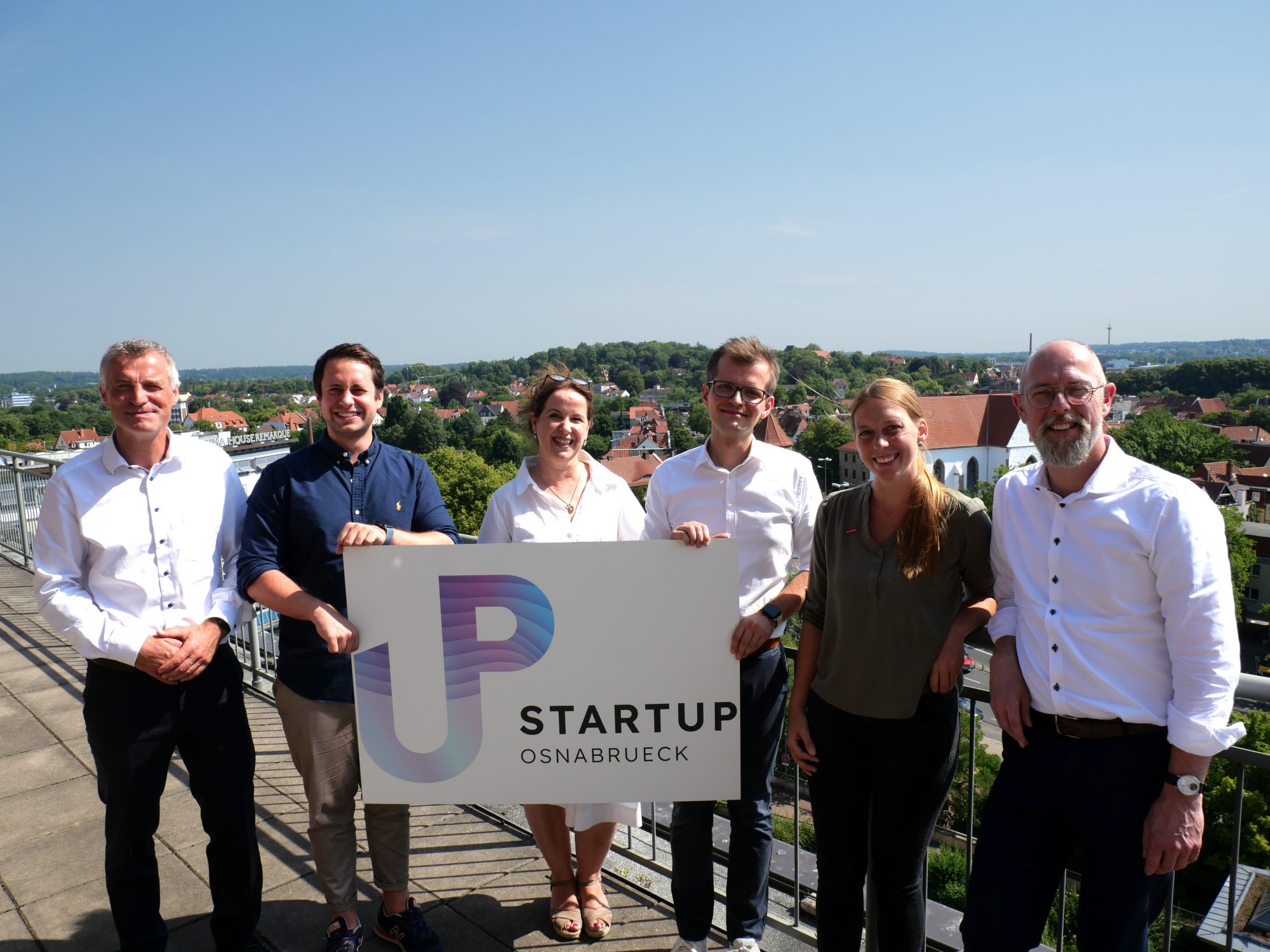 Präsentieren das neue Logo von Startup Osnabrück bei sommerlichem Wetter auf dem Balkon des Osnabrücker Stadthauses (vlnr.): Ralf Minning (WFO), Niklas Schwichtenberg (Aloys & Brigitte Coppenrath Stiftung), Prof. Dr. Karin Schnitker (Hochschule Osnabrück), Lars Brendler (WFO), Annika Hörnschemeyer (HWK) und Frank Hesse (IHK). (Foto: WFO)