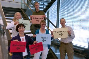 Präsentation des von Studierenden entwickelten Leitsystems zur Orientierung während des Fach- und Messetages: Dr. Eva Maria Schepers (Leitung des Westf. Instituts für Entwicklungsförderung) und Prof. Dr. Christian Huppert (FH Bielefeld) (hinten) mit Christiane Möcker (Mitarbeiterin des Planungsteams), Vera Trocha (Rehakoordinatorin, Fortbildungsakademie der Wirtschaft (FAW) gGmbH) und Markus Schneider (Autismus OWL e.V.) (Foto FH Bielefeld)