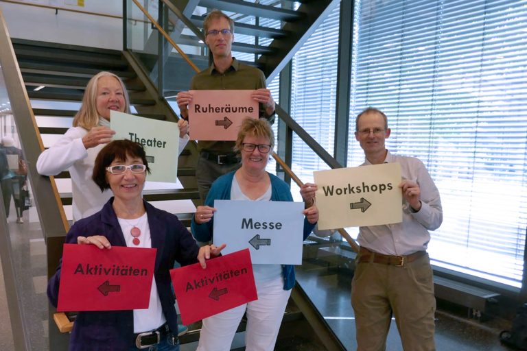 Präsentation des von Studierenden entwickelten Leitsystems zur Orientierung während des Fach- und Messetages: Dr. Eva Maria Schepers (Leitung des Westf. Instituts für Entwicklungsförderung) und Prof. Dr. Christian Huppert (FH Bielefeld) (hinten) mit Christiane Möcker (Mitarbeiterin des Planungsteams), Vera Trocha (Rehakoordinatorin, Fortbildungsakademie der Wirtschaft (FAW) gGmbH) und Markus Schneider (Autismus OWL e.V.) (Foto FH Bielefeld)