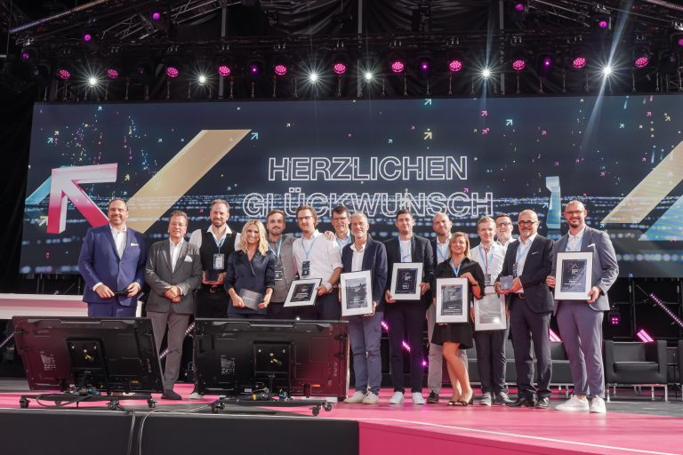 BVMW und Telekom verleihen Digital X Award an Nölle + Nordhorn, Rauschenberger, Select, Emons, German Volunteers und #WeAreAllUkrainians (auf dem Bild von links: Hagen Rickmann und Markus Jerger, BVMW, die Sieger und Moderatorin Michelle Hunziker). (Foto: Deutsche Telekom)