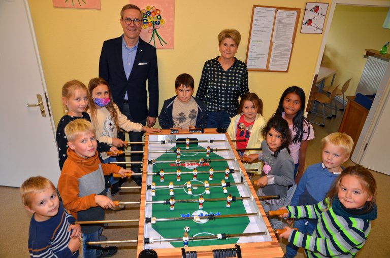 Im Namen der Paul und Karin Gauselmann Stiftung übergibt Mario Hoffmeister den Kicker an die Grundschule Preußisch Oldendorf. Neben OGS-Leiterin Helena Feer freuen sich besonders die Kinder über die neue Spielmöglichkeit. (Foto: Gauselmann Stifung)