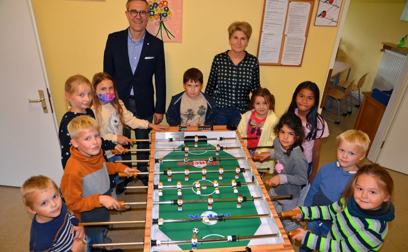 Im Namen der Paul und Karin Gauselmann Stiftung übergibt Mario Hoffmeister den Kicker an die Grundschule Preußisch Oldendorf. Neben OGS-Leiterin Helena Feer freuen sich besonders die Kinder über die neue Spielmöglichkeit. (Foto: Gauselmann Stifung)