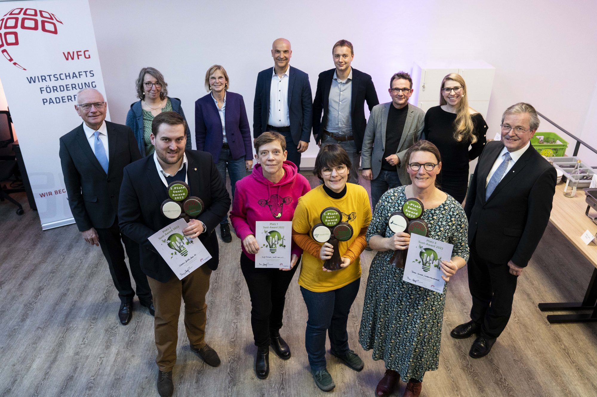 Die Sust-Award-Preisträgerinnen und Preisträger (vorne v.l.): Steffen Jesper (Gröne Unternehmensfamilie AG), Jutta Seiling und Anja Pötting (Vauß-Hof e.V.), Petra Kaiser (Linsenmanufaktur) zusammen mit (v.l.) Hans-Bernd Janzen (stv. Landrat), der Jury: Christa Hesse (Gemeinwohl-Ökonomie Paderborn), Heike Süß (Wirtschaftsförderung Paderborn), Prof. Dr. Carsten Padberg (FHDW) und Steve Flechsig (Westfalen Weser Netz GmbH) und Uwe Schoop (Prokurist der Wirtschaftsförderung Paderborn), Jessica Krüger (WFG) sowie Bürgermeister Michael Dreier. (Foto WFG/Tobias Vorwerk)