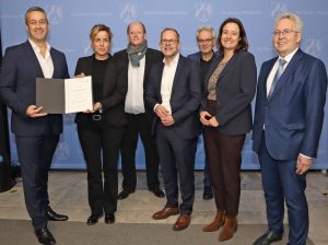 Feierliche Übergabe in Düsseldorf: VHK-Vorsitzender Andreas Wagner nimmt den Förderbescheid für die Lehrfabrik Möbelindustrie aus den Händen der nordrhein-westfälischen Wirtschaftsministerin Mona Neubaur entgegen. Über die Förderzusage freuten sich außerdem: Lehrfabrik-Projektleiter Markus Kamann, Verbandsgeschäftsführer Jan Kurth, Josef Wegener (Dezernatsleiter bei der Bezirksregierung Detmold), die Detmolder Regierungspräsidentin Anna Katharina Bölling und Landrat Jürgen Müller. (von links nach rechts) (Foto: VHK)