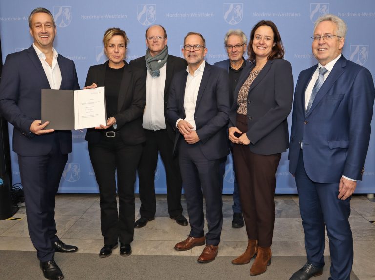 Feierliche Übergabe in Düsseldorf: VHK-Vorsitzender Andreas Wagner nimmt den Förderbescheid für die Lehrfabrik Möbelindustrie aus den Händen der nordrhein-westfälischen Wirtschaftsministerin Mona Neubaur entgegen. Über die Förderzusage freuten sich außerdem: Lehrfabrik-Projektleiter Markus Kamann, Verbandsgeschäftsführer Jan Kurth, Josef Wegener (Dezernatsleiter bei der Bezirksregierung Detmold), die Detmolder Regierungspräsidentin Anna Katharina Bölling und Landrat Jürgen Müller. (von links nach rechts) (Foto: VHK)