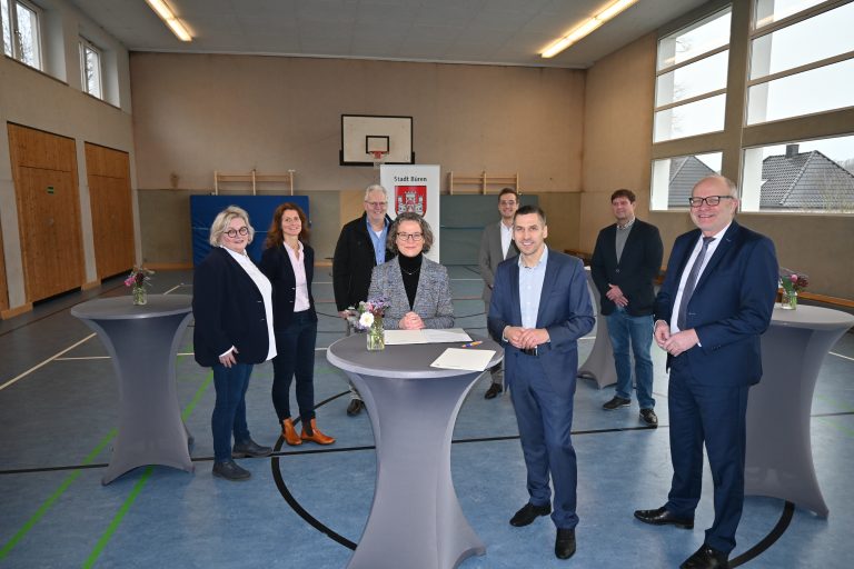 Bei der Übergabe des Zuwendungsbescheids (hintere Reihe v. l.): Eva-Maria Wellen und Claudia Baum (Schulleiterin und stellvertretende Schulleiterin des Städtischen Grundschulverbunds Wegwarte), Rüdiger Bonke (Fraktionsvorsitzender Freie Wähler Bürger für Büren e. V.), André Stadermann (Abteilungsleiter Planen und Bauen, Stadt Büren) und Malte Brinkmann (Abteilung Planen und Bauen, Stadt Büren). Vordere Reihe (v. l.): Ina Scharrenbach (Ministerin für Heimat, Kommunales, Bau und Digitalisierung des Landes Nordrhein-Westfalen), Bürgermeister Burkhard Schwuchow und Bernhard Hoppe-Biermeyer (Mitglied des Landtags, CDU)(Foto: Stadt Büren)