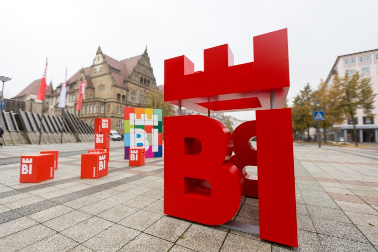 Aus dem Bielefelder Straßenbild ist es nicht mehr wegzudenken, man entdeckt es auf privaten Fahrzeugen, aber auch auf Polizei- und Rettungswagen, an öffentlichen Gebäuden und auf Plakaten: das Bielefelder Stadtlogo BIE. Es entstand 2016 im Rahmen des partizipativen Stadtmarkenprozesses - entwickelt von der Bielefelder Agentur deteringdesign. (Foto: Bielefeld Marketing)