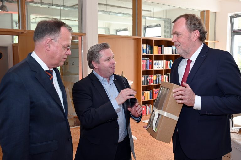 Bürgermeister Tim Kähler überreicht ein Gastgeschenk der Hansestadt Herford an Dr. Jost Streitbörger, Managing Partner der Sozietät Streitbörger. Links Dr. Matthias Rose, Partner. (Foto: Textransfer Communications)