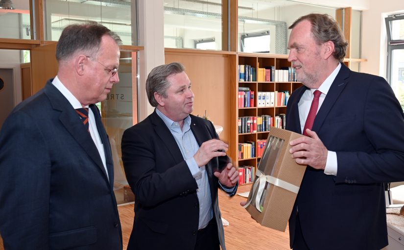 Bürgermeister Tim Kähler überreicht ein Gastgeschenk der Hansestadt Herford an Dr. Jost Streitbörger, Managing Partner der Sozietät Streitbörger. Links Dr. Matthias Rose, Partner. (Foto: Textransfer Communications)