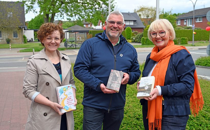 Natalia Neufeld (l.) und Maria Runde nahmen die Spende aus den Händen von Marcus Rüdiger entgegen. Mit einem Buch in der Hand zeigen die Drei schon einmal, wo der Bücherschrank aufge-stellt werden soll. (Foto: SWTE)