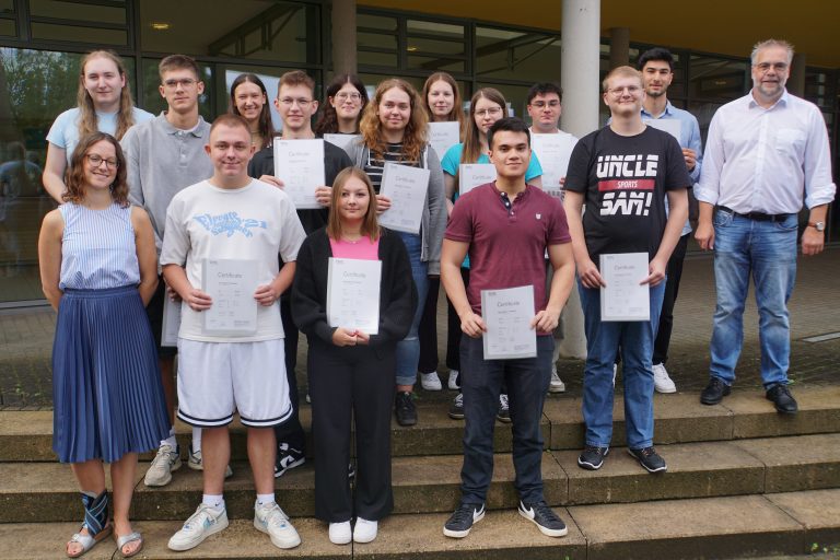 Schülerinnen und Schüler des HANSE-Berufskollegs mit Ihren TELC-Zertifikaten; unten links: Saskia Reiners (Europakoordinatorin in Vertretung); hinten rechts: Heiko Jucks (stellv. Schulleiter) (Foto: HANSE-Berufskolleg Europaschule)