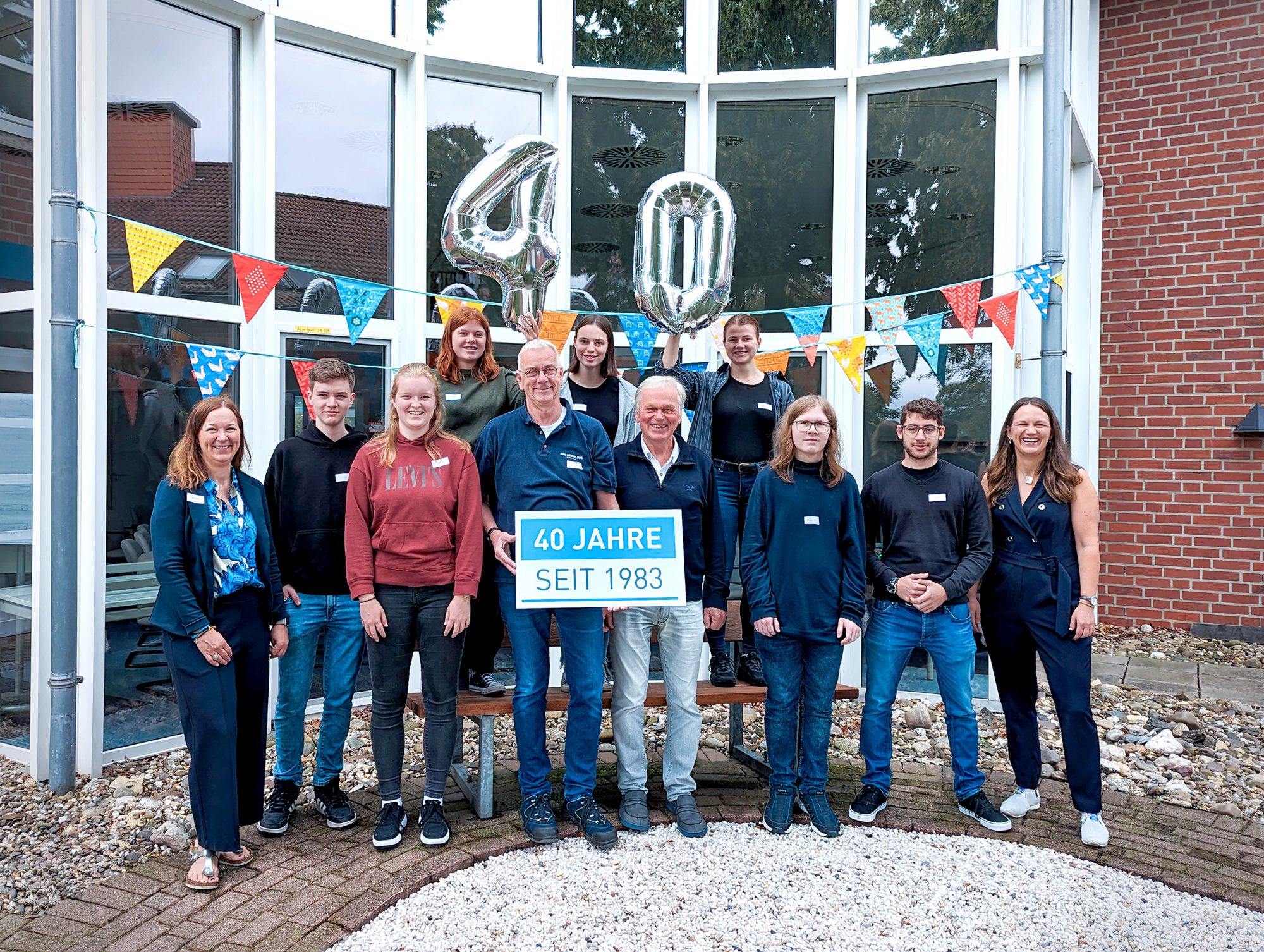 40 Jahre Unternehmenstradition in einem Bild: Die Unternehmerinnen Diana Weßling (li.) und Anna Weßling (re.) mit Unternehmensgründer Dr. Erwin Weßling (vorn, 4. v. re.) und der erste Auszubildende von 1983, Thomas Dalhoff (vorn, 5. v. re) begrüßen die sieben jungen Auszubildenden der WESSLING Gruppe zum Ausbildungsstart. (Foto: Wessling)