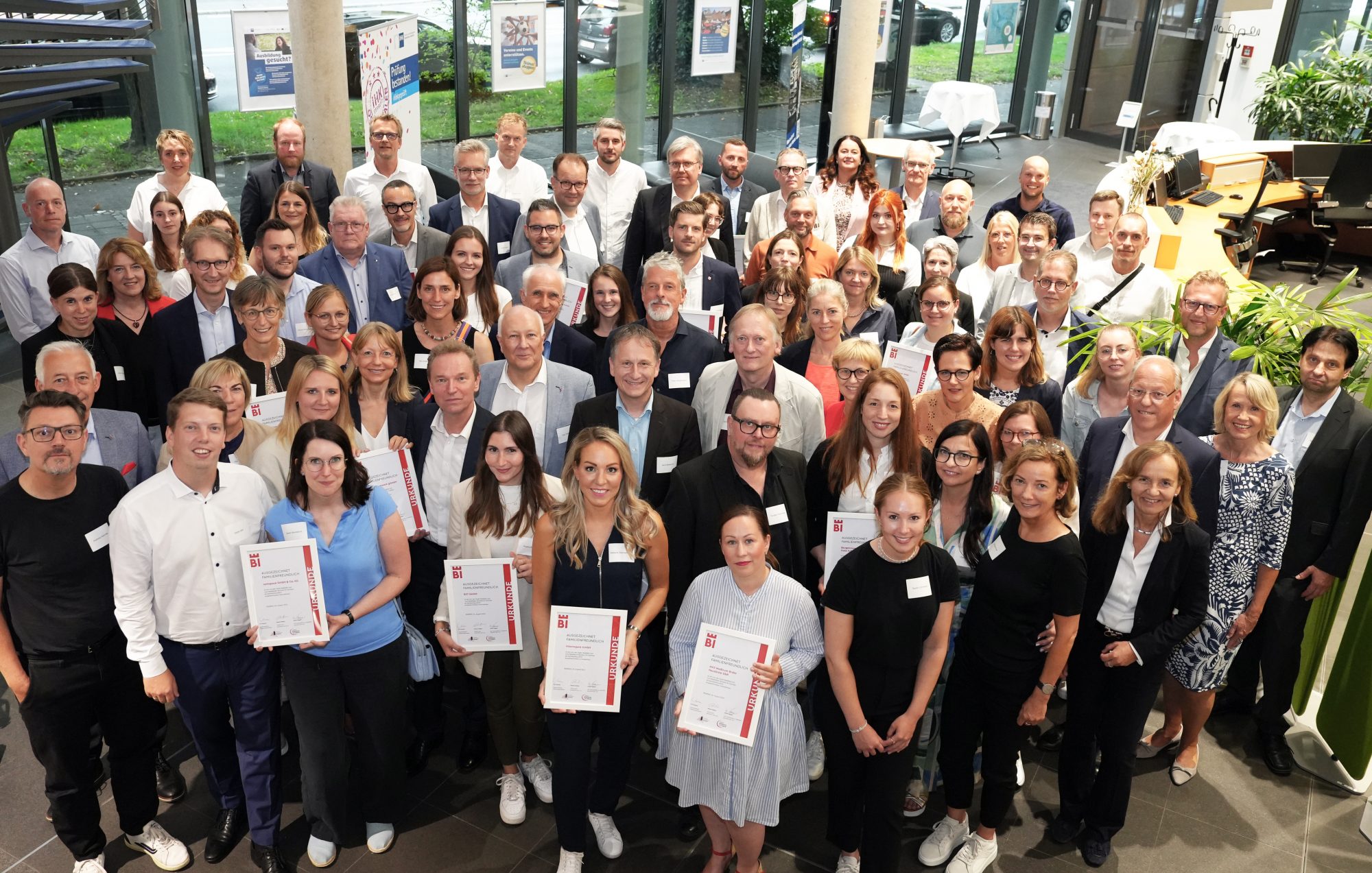 Vertreterinnen und Vertreter der 28 prämierten Unternehmen, der Jury und der Initiatoren des Wettbewerbs „Ausgezeichnet Familienfreundlich Bielefeld“ versammeln sich im Anschluss an die Feierstunde im Foyer der IHK Ostwestfalen zu Bielefeld (Bildnachweis: IHK Ostwestfalen zu Bielefeld)