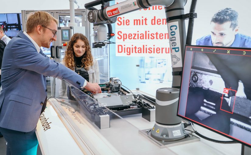 Ein Roboter für die Echtgeldprüfung: Henning Peters, wissenschaftlicher Mitarbeiter vom Fraunhofer IEM, präsentiert den in einem it’s OWL Projekt entstandenen kollaborativen Roboter (Cobot) auf der FMB – Fachmesse für Maschinenbau. Der Cobot soll Diebold Nixdorf beim Echtgeldtest von Geldautomaten und der Montageprüfung von Bedienfeldern an Geldautomaten unterstützen. (Foto: it's OWL)