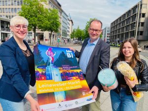 Katharina Schilberg, Martin Knabenreich und Karoline Jockheck (v. l.) von Bielefeld Marketing zeigen am Niederwall den Standort für den brandneuen „Nordic Tower“, womit Fans des Nervenkitzels durch die Lüfte fliegen können. Kein Leuchtturm in Europa soll höher als das Kettenkarussell mit 90 Metern Höhe sein. (Foto: Bielefeld Marketing GmbH)