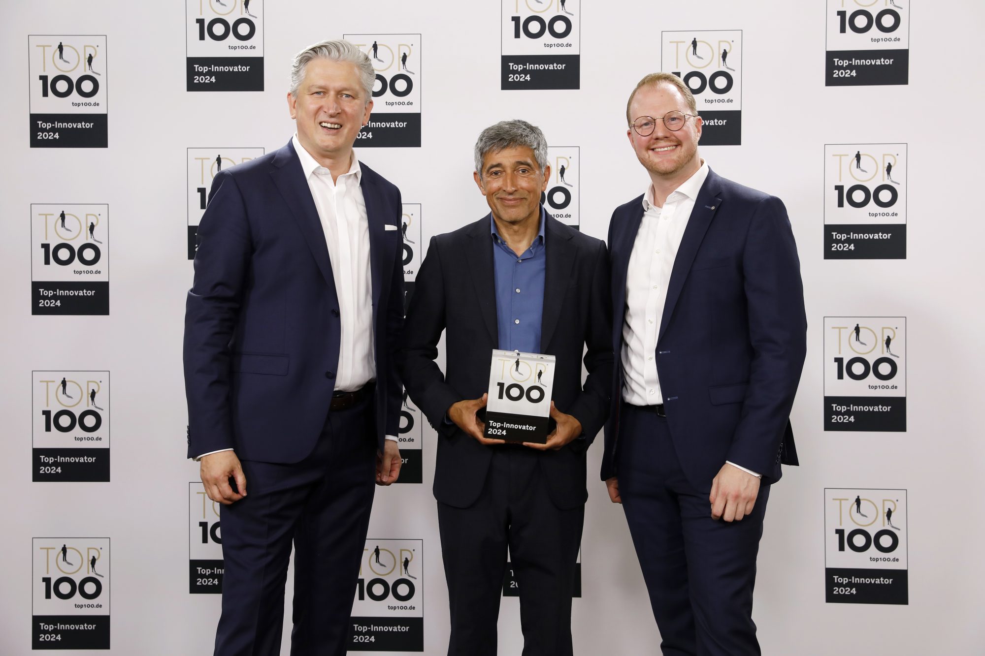 Aus den Händen von Ranga Yogeshwar, Mentor des Innovati-onswettbewerbs „TOP 100 Innovator“, erhielten Ansgar Käter (links), Vorstandsvorsitzender der VerbundVolksbank OWL, und Dr. Maximilian Jolmes (rechts), Bereichsleiter „Innovation & Digita-les“ der VerbundVolksbank OWL, die Auszeichnung. (Foto: VerbundVolksbank OWL)