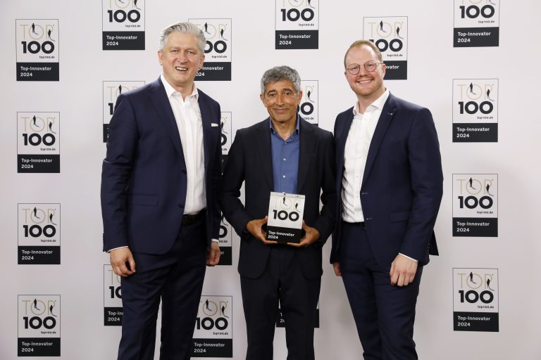 Aus den Händen von Ranga Yogeshwar, Mentor des Innovati-onswettbewerbs „TOP 100 Innovator“, erhielten Ansgar Käter (links), Vorstandsvorsitzender der VerbundVolksbank OWL, und Dr. Maximilian Jolmes (rechts), Bereichsleiter „Innovation & Digita-les“ der VerbundVolksbank OWL, die Auszeichnung. (Foto: VerbundVolksbank OWL)