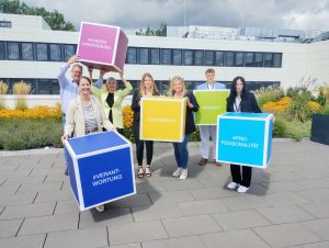 Unternehmenswerte kreativ präsentiert: Birgit Aspin (Chief People Officer und Mitglied der Geschäftsleitung) sowie (v. l.) Frank Schultz (Abteilungsleiter Direktservice und Ausbildungswerkstatt), Nadja Bürger (Leiterin Geschäftsfeld Ambulantes Gesundheitswesen, Direktservice und Ausbildungswerkstatt und Mitglied der Geschäftsleitung) und Leonie Münnich (Direktservice-Team / Ausbildungswerkstatt), Pia Stohlmann (Referentin Personalentwicklung) begrüßen mit Niklas Kehne (Auszubildender zum Kaufmann für Versicherungen und Finanzen) und Lilli Richter (Auszubildende zur Kauffrau für Versicherungen und Finanzen) zwei der neuen Auszubildenden. (Foto: Ecclesia Gruppe)