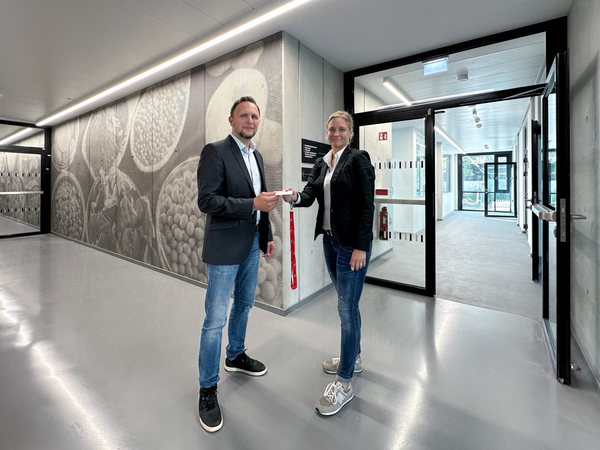 Silke Grote, die Planerin und Projektverantwortliche des Bau- und Liegenschaftsbetrieb NRW, übergibt symbolisch eine Schlüsselkarte für das neue Gebäude an Sergej Roth, den stellvertretenden Leiter des Dezernats Gebäudemanagement der Technischen Hochschule OWL. (Foto: Pilz, BLB NRW)