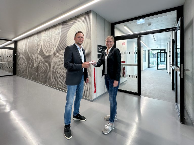 Silke Grote, die Planerin und Projektverantwortliche des Bau- und Liegenschaftsbetrieb NRW, übergibt symbolisch eine Schlüsselkarte für das neue Gebäude an Sergej Roth, den stellvertretenden Leiter des Dezernats Gebäudemanagement der Technischen Hochschule OWL. (Foto: Pilz, BLB NRW)