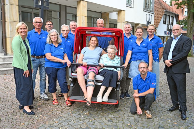 Stadtwerke-Geschäftsführer Tobias Koch (r.) überreichte die Spende in Höhe von 1.500 Euro an den Vorsitzenden des DRK-Ortsvereins, Jens Kümper (hinten, 4.v.r.), und das Ehrenamtlichen-Team. Die Empfänger und Bürgermeisterin Christina Rählmann (l.) freuten sich sehr über die Zuwendung. Zum Fototermin genossen Ursula Reckers (r.) und ihre Tochter Nicole Meyer eine kleine Ausfahrt mit der Rikscha. (Foto: SWTE)