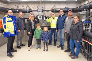 Sie warfen gemeinsam einen Blick in die Technikzentrale, dem Herzstück im Kalte-Nahwärme-Netz: (v.l.) SWTE Netz-Geschäftsführer Tobias Koch, Bauamtsleiter Felix Sieker, Bürgermeisterin Christina Rählmann, Ian und Hailee, SWTE Netz-Meister Andre Schröer, SWTE Netz-Ingenieur Kai Watermeyer sowie Nico und Denise Kleingünther. (Foto: SWTE Netz GmbH & Co. KG)