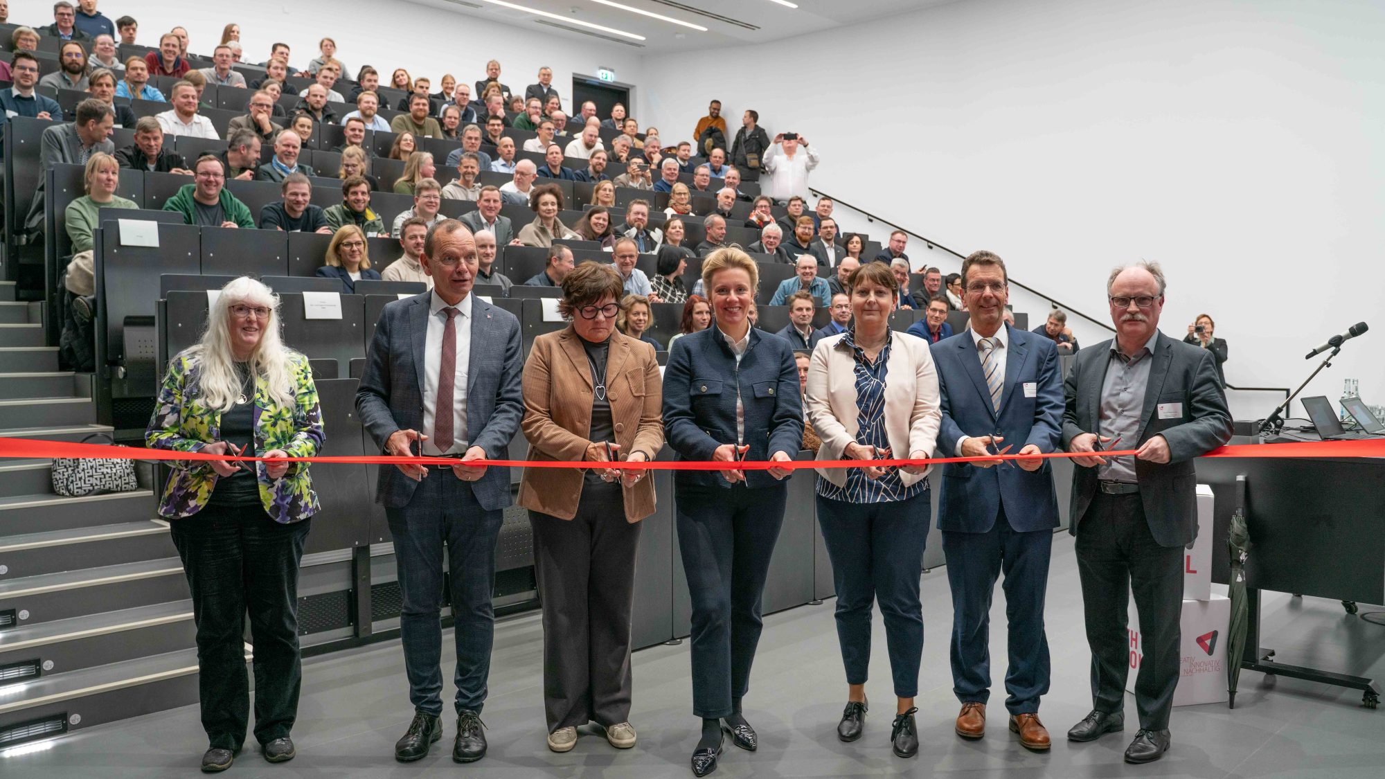 Für die symbolische Eröffnung zerschnitten das Band (v.l.): Professorin Petra Meier, TH-OWL-Präsident Professor Jürgen Krahl, BLB NRW-Geschäftsführerin Gabriele Willems, Ministerin Ina Brandes, TH-OWL-Kanzlerin Nicole Soltwedel, Professor Thomas Gassenmeier sowie Professor Thomas Schulte. (Foto: TH OWL)