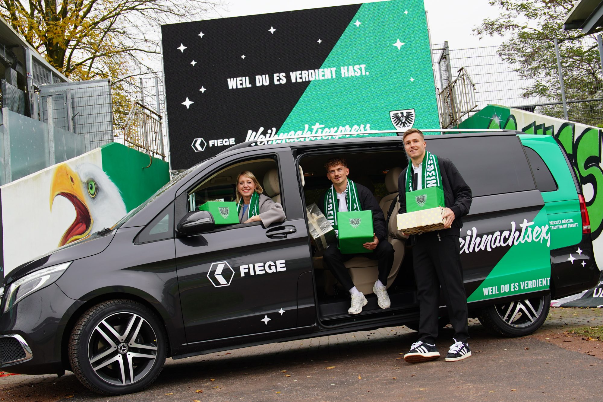 Vorweihnachtliche Bescherung: Die Preußen-Kicker Thorben Deters (m.) und Joel Grodowski (r.) sowie Sarah Schimmelpfennig, Executive Director Marketing & Communications bei Preußen-Hauptsponsor Fiege, gehen auch in diesem Jahr mit dem Fiege-Weihnachtsexpress auf Überraschungs-Tour durchs Münsterland. (Foto: SC Preußen Münster)