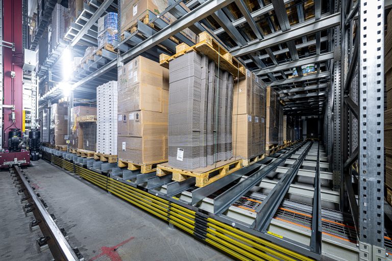 Ein Satellitenlager® von Westfalia Technologies – hier das Verpackungslager der Züger Frischkäse AG – lagert hochkompakt und materialschonend. Dank der mehrfachen Schienenauflage in den Lagerkanälen halten Paletten länger. Das verhindert Störungen und Ausfallzeiten. (Foto: Westfalia Technologies GmbH & Co. KG / Marcello Engi)