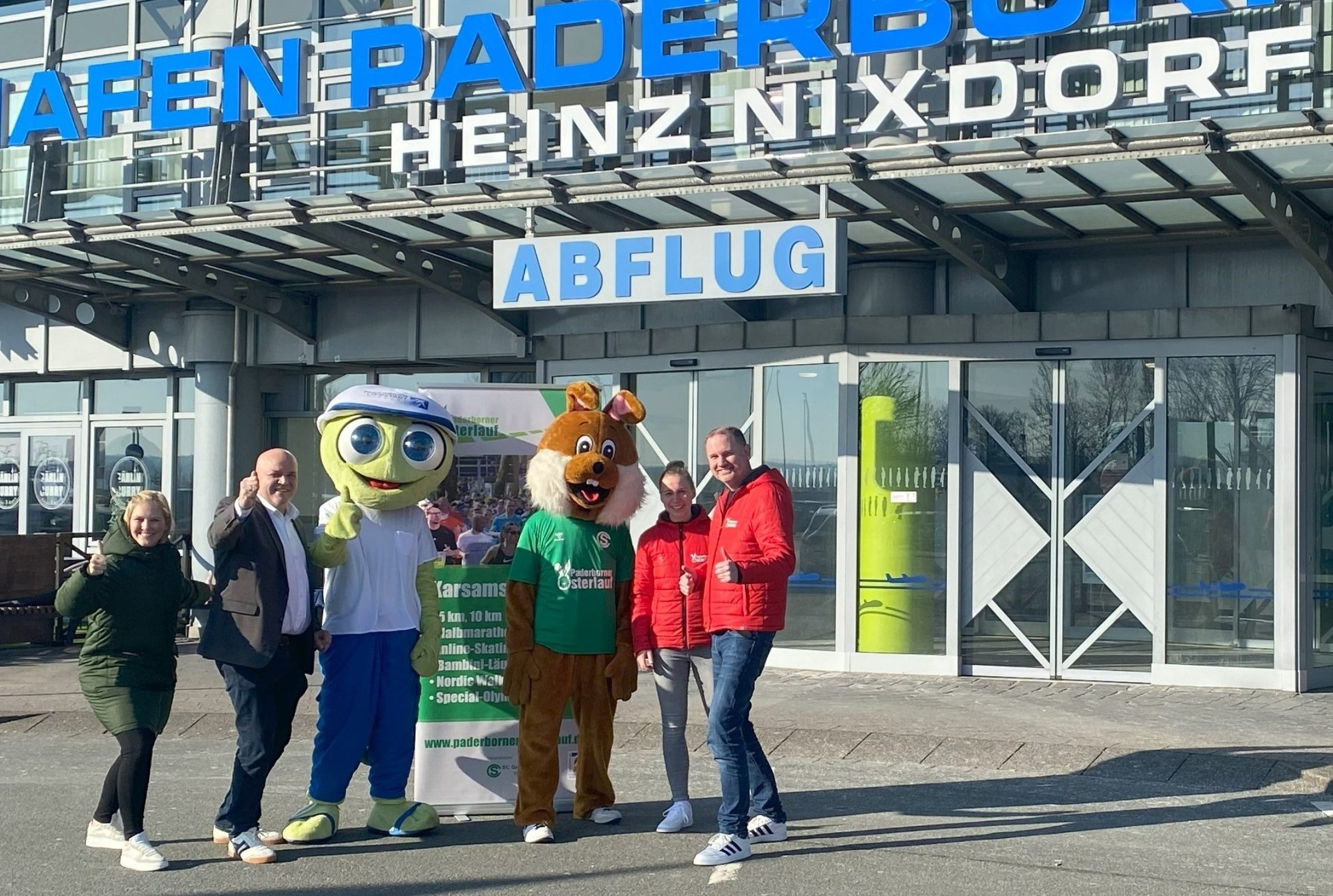 Partner beim Paderborner Osterlauf 2025 (von links): Luisa Peitz (Marketing, Flughafen Paderborn/Lippstadt), Roland Hüser (Geschäftsführer, Flughafen Paderborn/Lippstadt) und Maskottchen Homie freuen sich gemeinsam mit Osterlauf-Maskottchen Paola sowie Mareen Walbaum (Sportmanagerin, SC Grün-Weiß Paderborn) und Christian Stork (Organisationsleiter, Osterlauf) auf den 6. Paderborn/Lippstadt Airport 5 km Fit and Fun Lauf. (Foto: Flughafen Paderborn/Lippstadt)