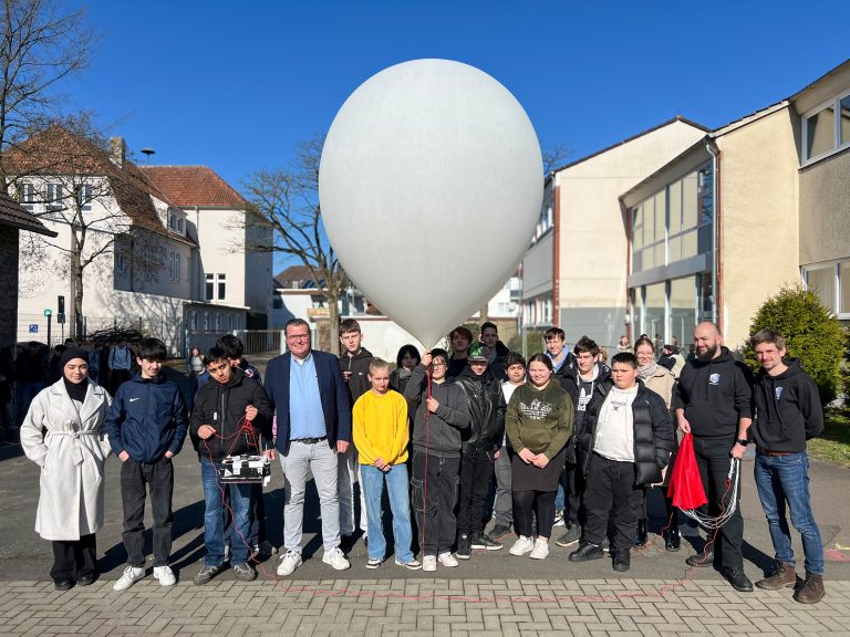 Der Ballon ist gefüllt. Gleich geht's ab in den Himmel: Fünfter von rechts: Thomas Mahlmann (zdi-Zentrum Lippe.MINT), von links: Marvin Rissiek und Robin Odasso (beide Stratoflights GmbH & Co. KG) mit den teilnehmenden Schülerinnen und Schülern. (Foto: Lippe Bildung eG)