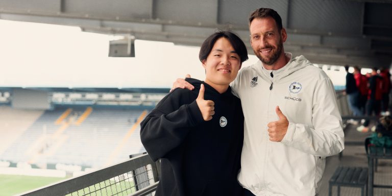 Seine Fußballbegeisterung hat ihn von Japan nach Bielefeld geführt: Dass Takaaki Hagiwara beim Fotoshooting in der Schüco-Arena überraschend auf Cheftrainer Mitch Kniat trifft, war für ihn ein absolutes Highlight! (Foto: P. Pollmeier / HSBI)