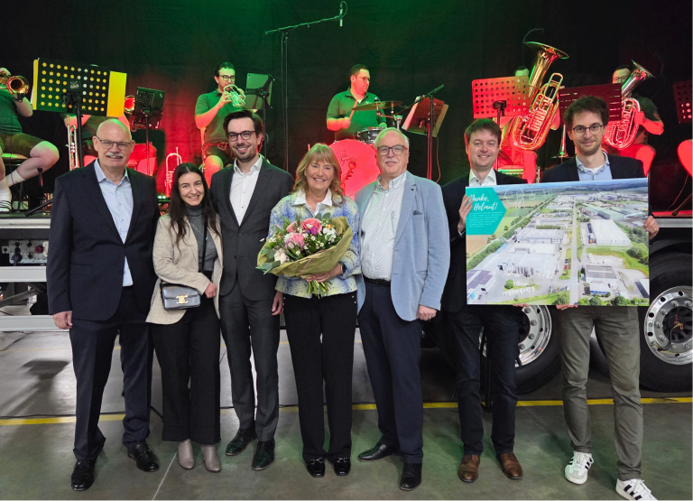 Vertreter der Familien Hirsch und Grafe stehen bei einer Feierstunde zur Übergabe von ARGUS an die nächste Generation vor einer Bühne.