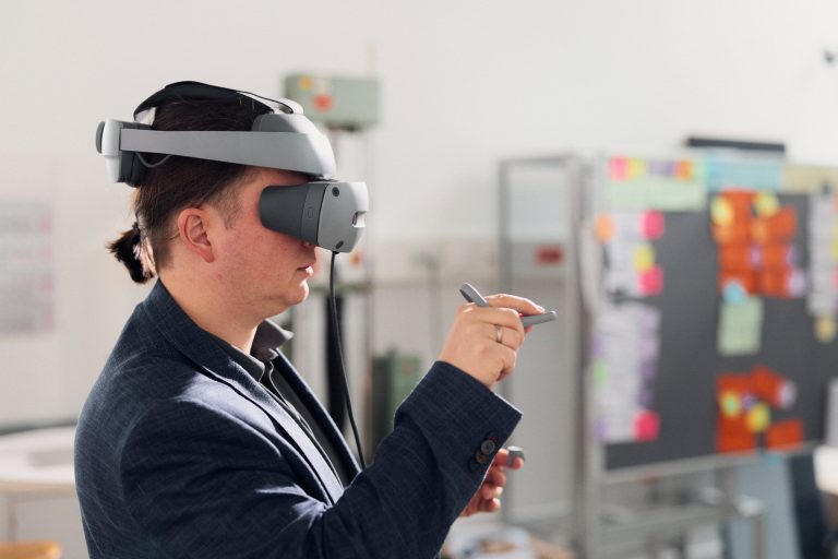 Person im VR-Labor der Hochschule Bielefeld mit Sony-XR-Brille und Eingabestift bei der Arbeit an einer virtuellen Konstruktion
