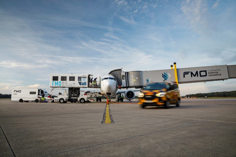 Passagierflugzeug am Gate auf dem Vorfeld des Flughafens Münster/Osnabrück mit Bodenfahrzeugen und Fluggastbrücke